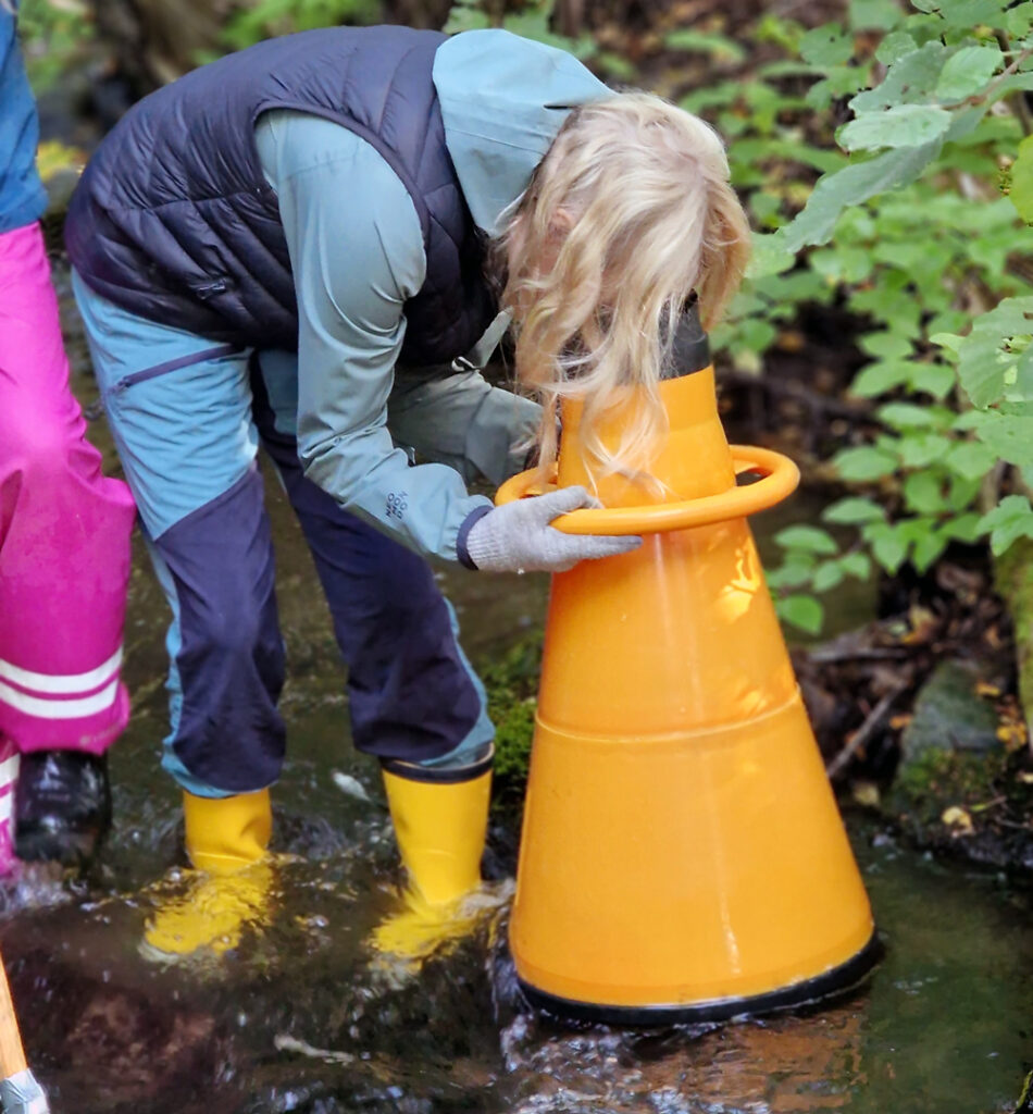 Elev som studerar miljön i ett vattendrag genom vattenkikare.